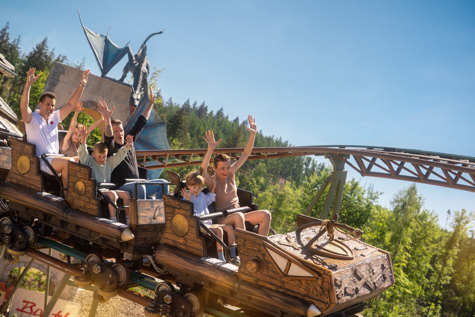 Familie mit erhobenen Armen in der Drachen-Achterbahn im Taunus Wunderland
